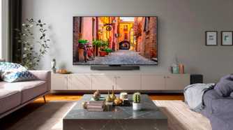 An image showing the LG C3 OLED TV mounted on a wall in a living room with couches and other furniture.
