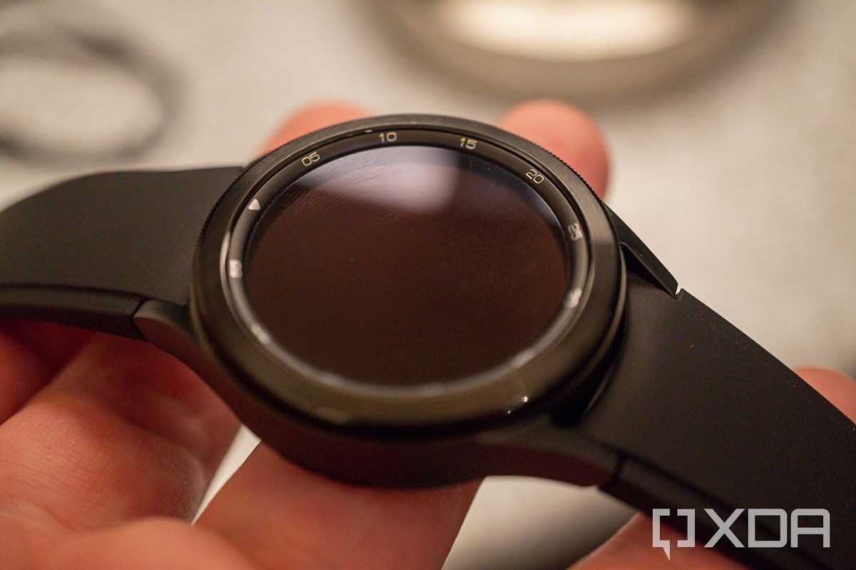 A Samsung Galaxy Watch 4 Classic held in someone's fingers