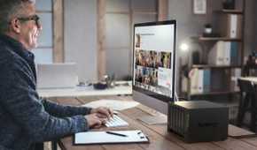 Synology diskstation 1522 plus network attached storage on a desk next to a man working on a computer
