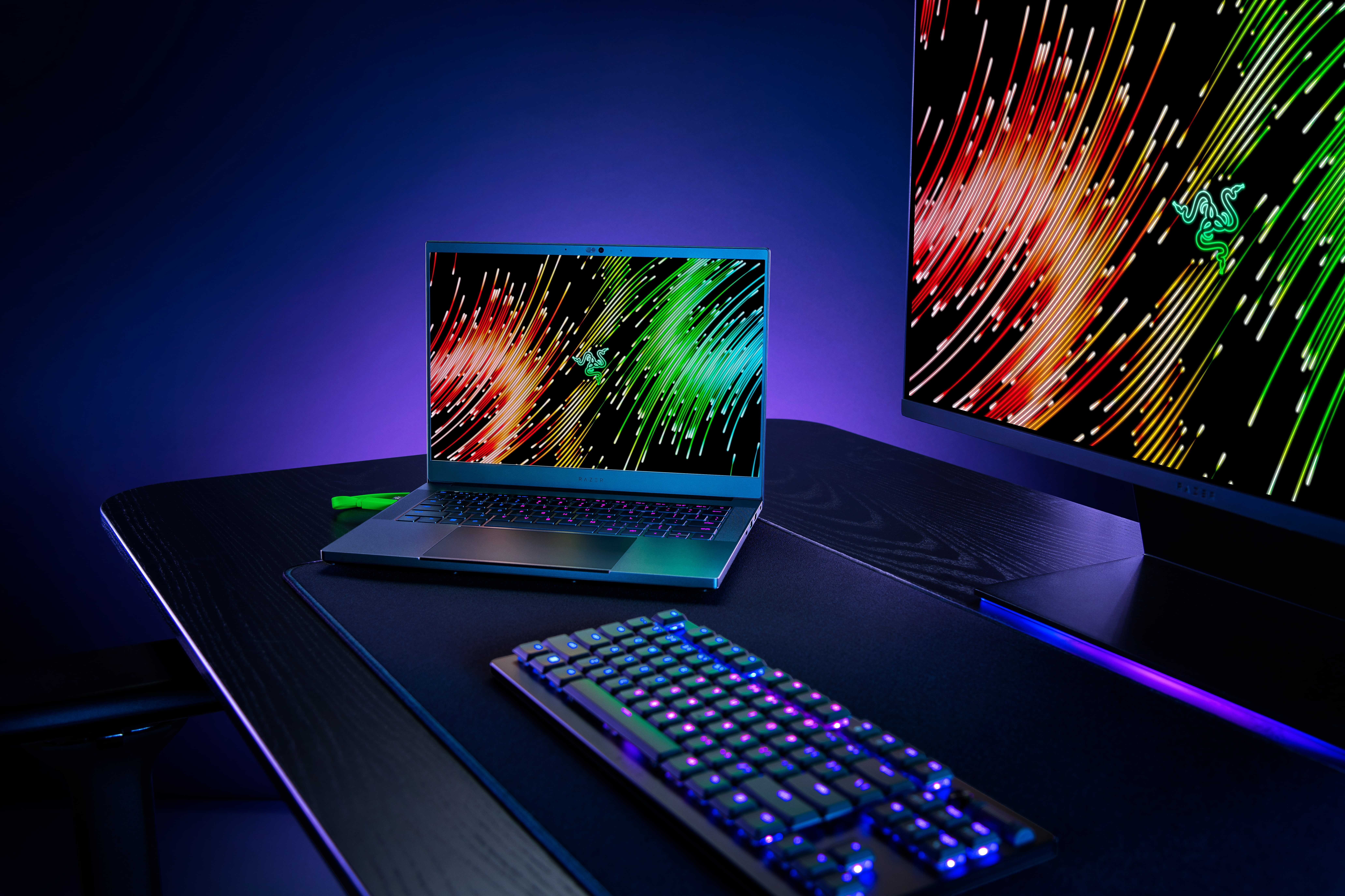 A Razer Blade 14 on a desk next to computer peripherals, including a monitor and keyboard.