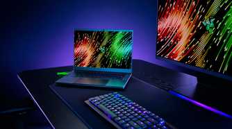 A Razer Blade 14 on a desk next to computer peripherals, including a monitor and keyboard.