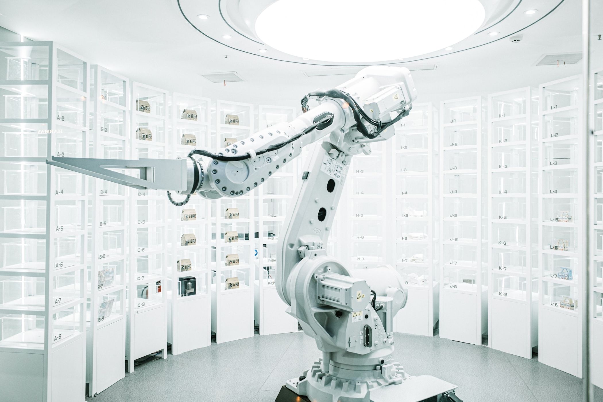 A futuristic, brightly-lit white room with a robotic machine