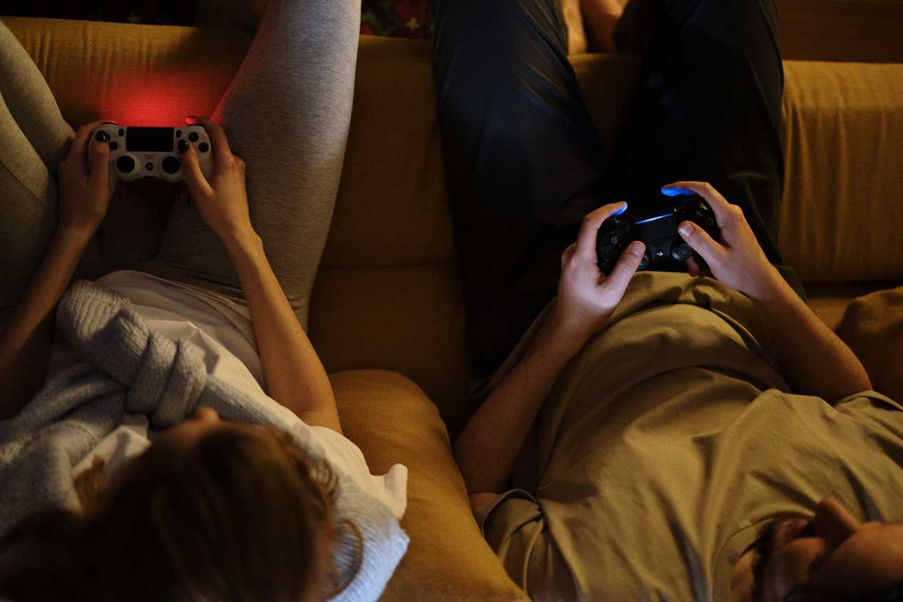 Couple on sofa with controllers in hands playing console game