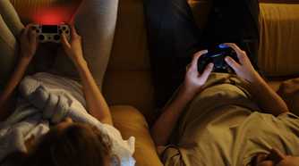 Couple on sofa with controllers in hands playing console game