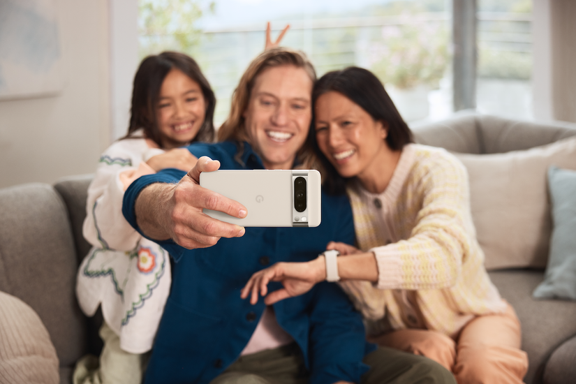 A person holding the Pixel 8 Pro horizontally to take a group selfie with two others in the frame.