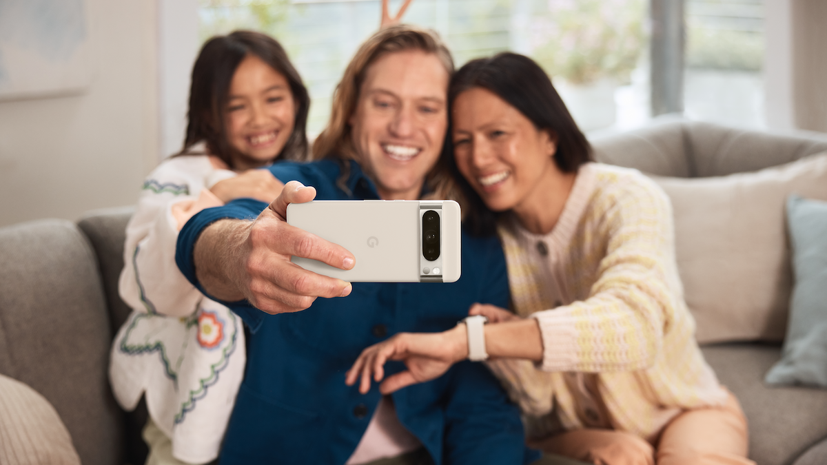 A person holding the Pixel 8 Pro horizontally to take a group selfie with two others in the frame.