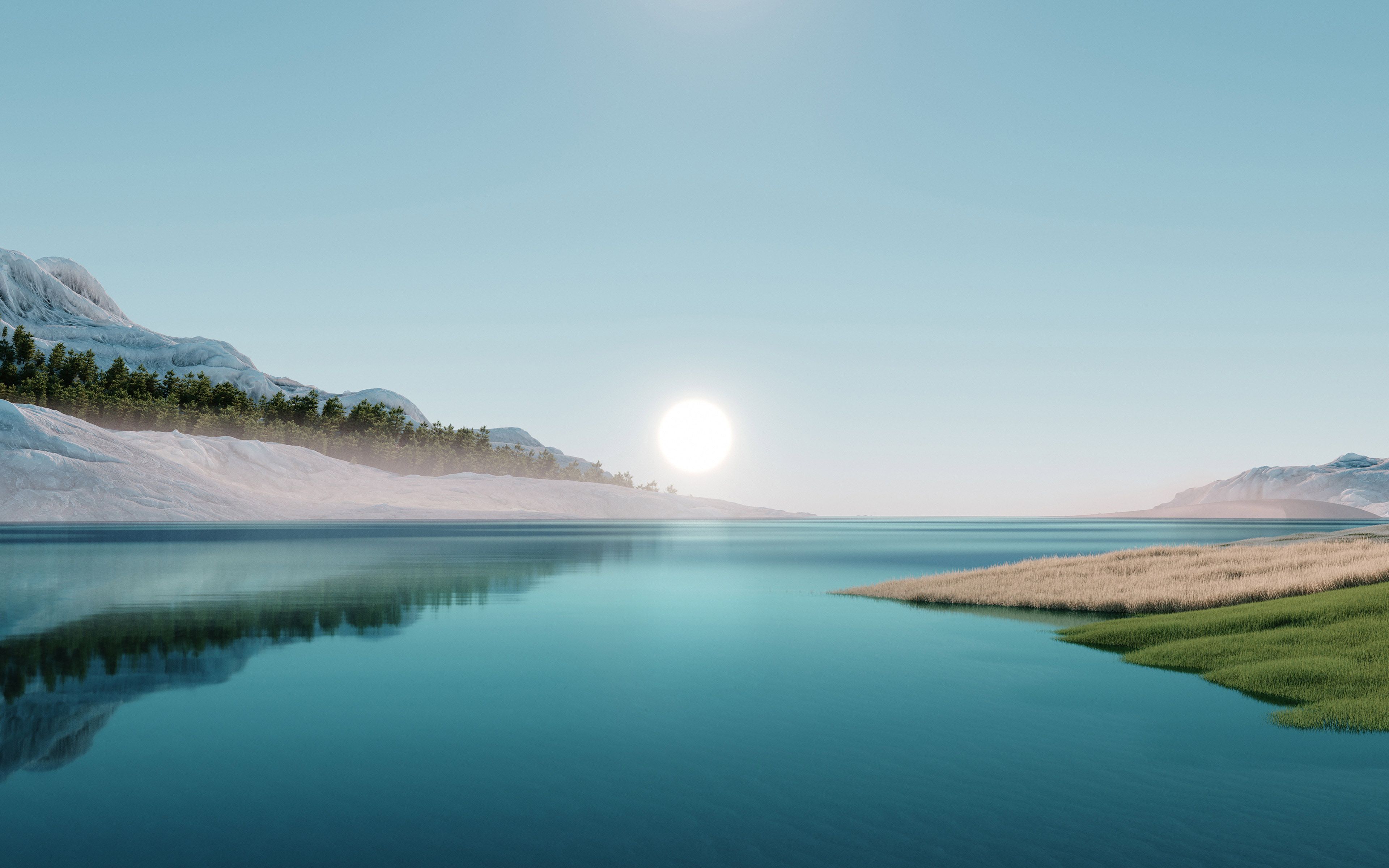 A clear lake surrounded by grassy landscapes and snow-covered mountains