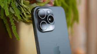 iPhone 15 Pro Max in black titanium leaning against some plants