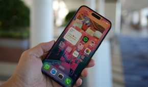 The iPhone 15 Pro Max in the hand with the screen on.
