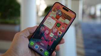 The iPhone 15 Pro Max in the hand with the screen on.