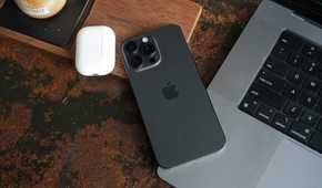 iPhone 15 Pro Max lying on a laptop.