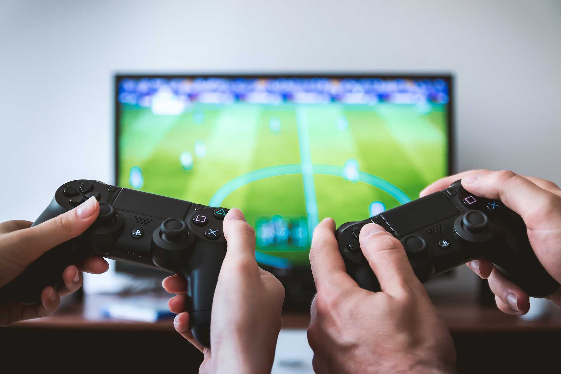 Two people showing hands holding PS4 controllers
