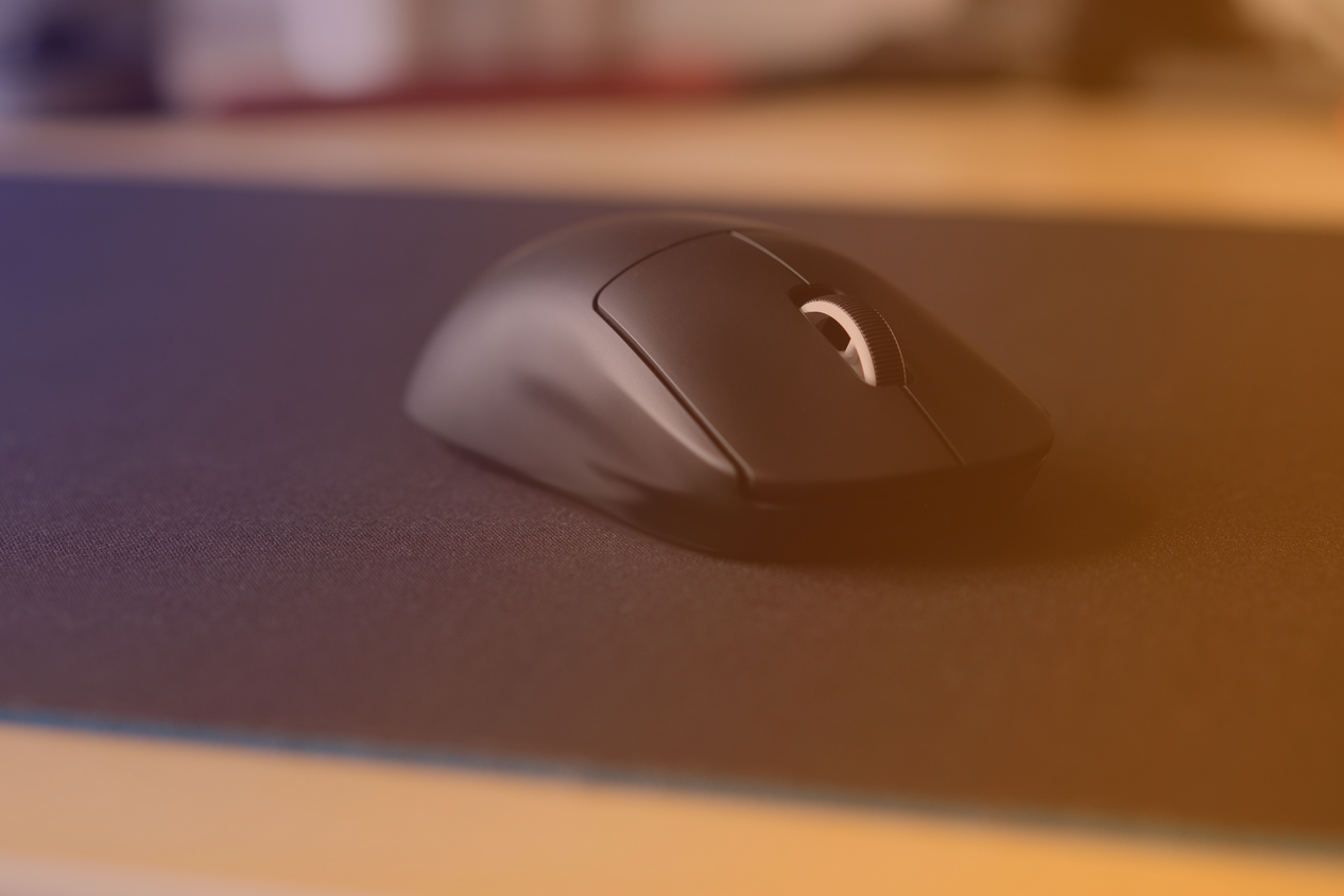 A gaming mouse on a large gaming mouse pad with a purple to orange hue