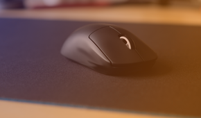 A gaming mouse on a large gaming mouse pad with a purple to orange hue