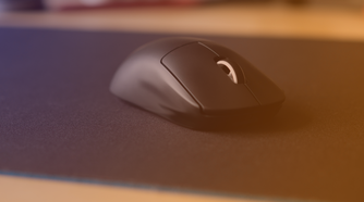 A gaming mouse on a large gaming mouse pad with a purple to orange hue