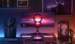 A full Lenovo computer setup to the right, custom RGB backlighting desktop with wallpapers on the wall, a Lenovo laptop to the left, and the Legion Go is in the middle under the computer monitor