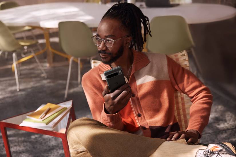 A man holding a Pxixel 8 Pro while sitting cross-legged.