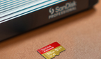 A SanDisk Extreme 512GB microSDXC card on a table beside a card reader.