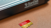 A SanDisk Extreme 512GB microSDXC card on a table beside a card reader.