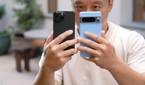 A dude holding the iPhone 15 Pro Max and Google Pixel 8 Pro in his hands