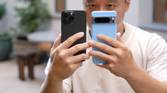 A dude holding the iPhone 15 Pro Max and Google Pixel 8 Pro in his hands