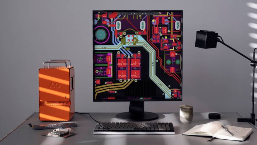 An image showing desk with Teenage Engineering Computer-1 PC case, a monitor and other desk peripherals and accessories next to it.