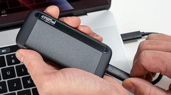 Crucial X8 Portable SSD in hand being plugged into computer