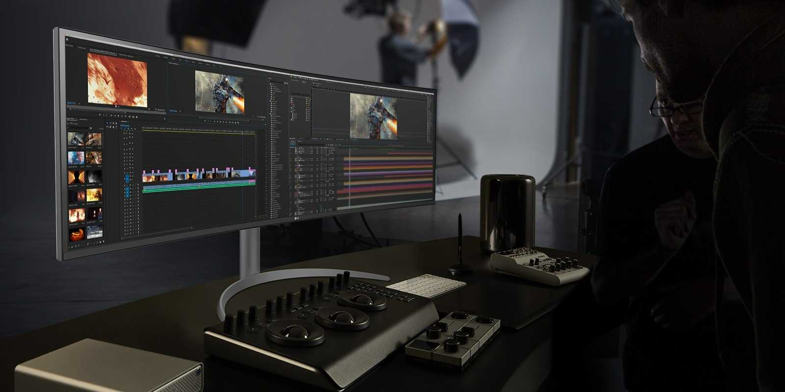 An LG UltraWide 49WQ95C monitor on a desk next to mixing tools used for editing video professionally