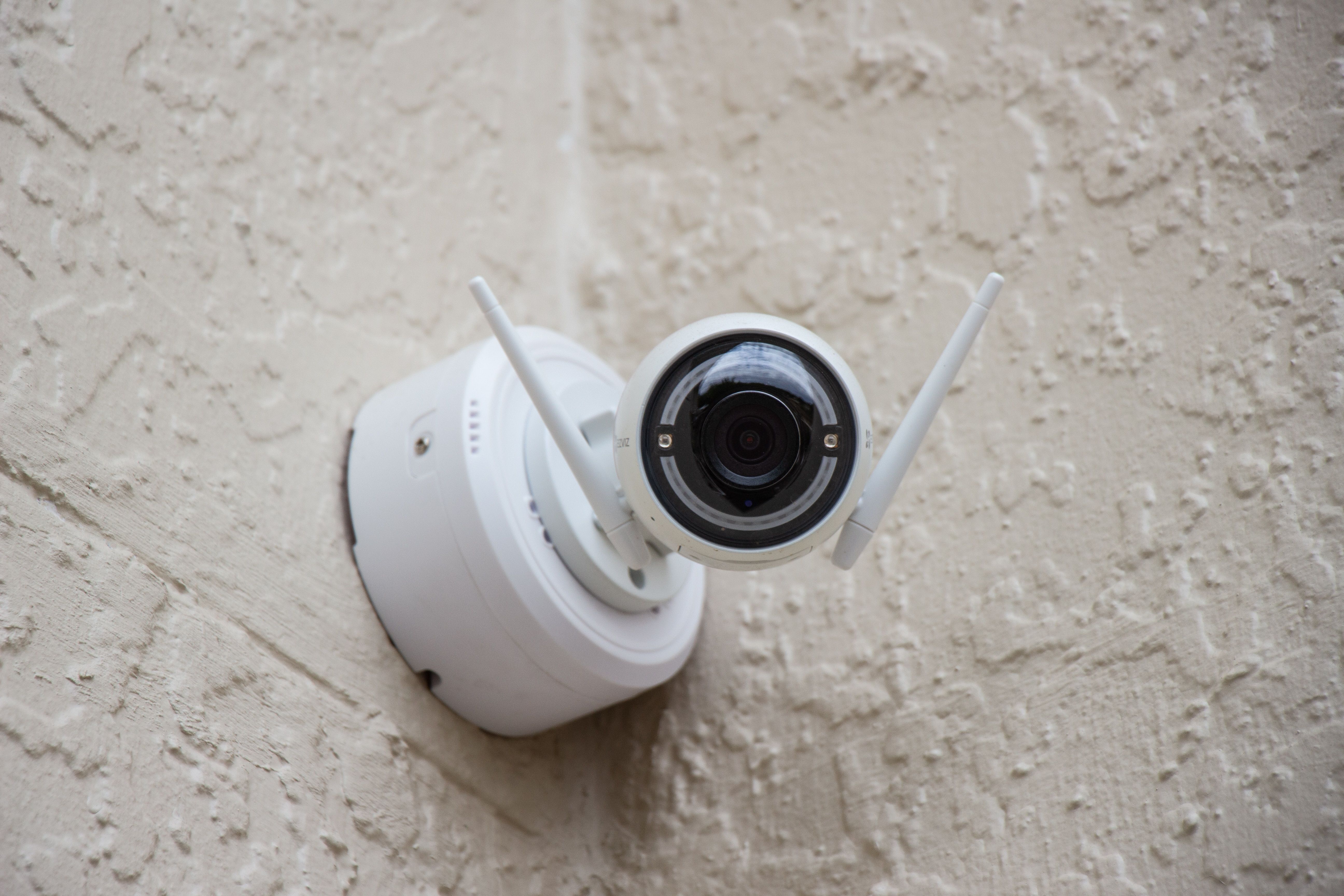 Security camera with wireless antenna on tan wall