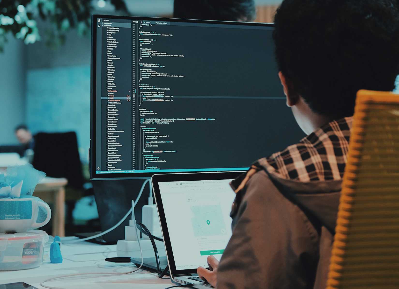 An image of a person programming on a Macbook Pro and Pro Display XDR.