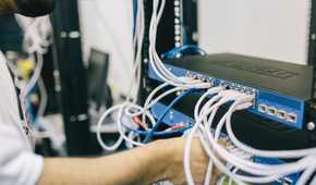 Man working on a network switch by plugging in ethernet cable