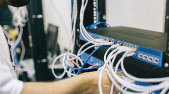 Man working on a network switch by plugging in ethernet cable