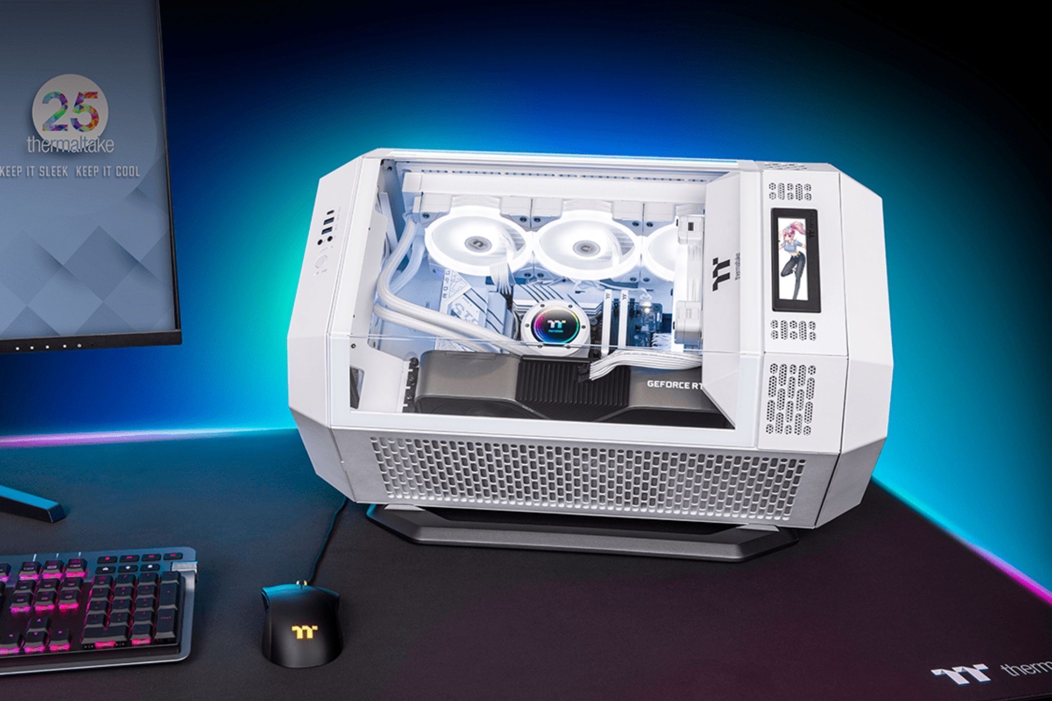 An image showing the Thermaltake The Tower 300 PC case resting on a table next to a monitor.