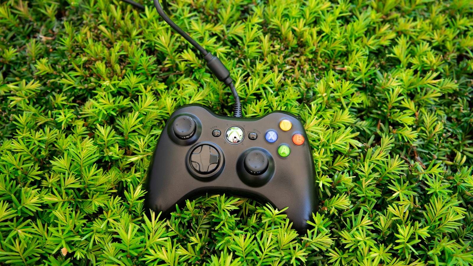 An image of an Xbox 360 controller lying on grass
