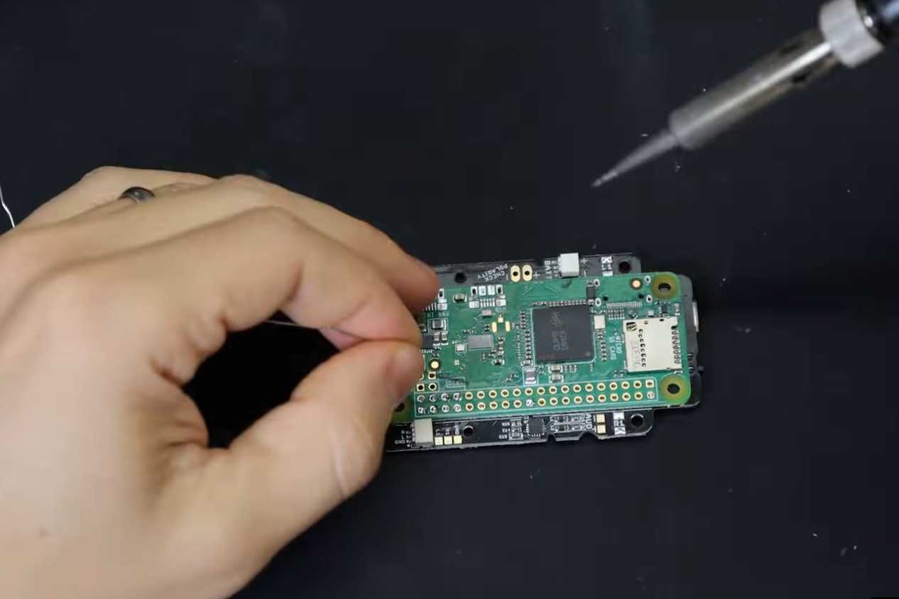A screenshot showing a person soldering a Raspberry Pi module to onto a PCB.