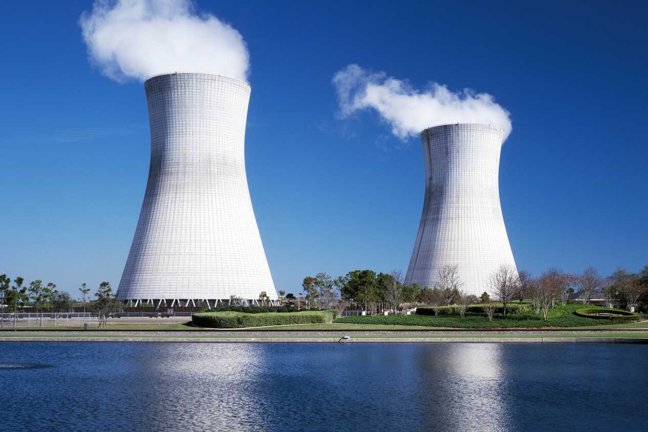 A nuclear power plant emitting smoke near a water body