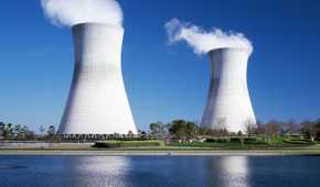 A nuclear power plant emitting smoke near a water body