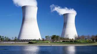 A nuclear power plant emitting smoke near a water body
