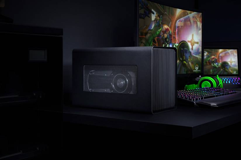 A Razer Core X Chroma in a gaming setup including a laptop, monitor, keyboard, and headphones