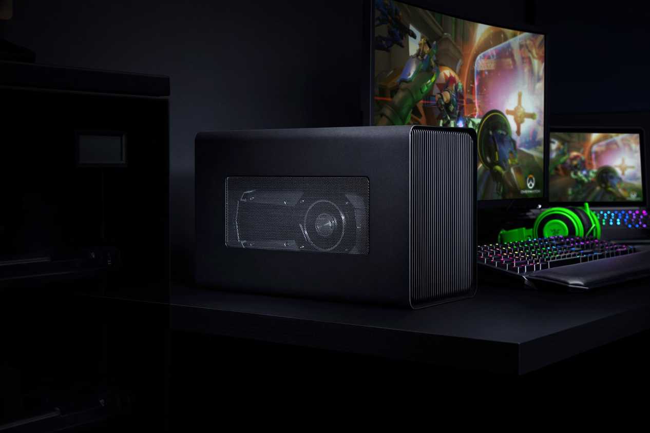 A Razer Core X Chroma in a gaming setup including a laptop, monitor, keyboard, and headphones