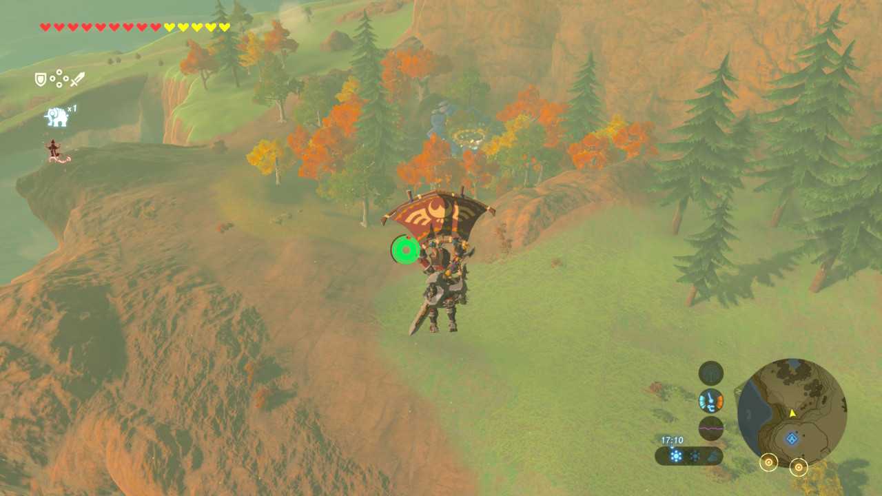 Link gliding over a field with grass and multi-colored trees