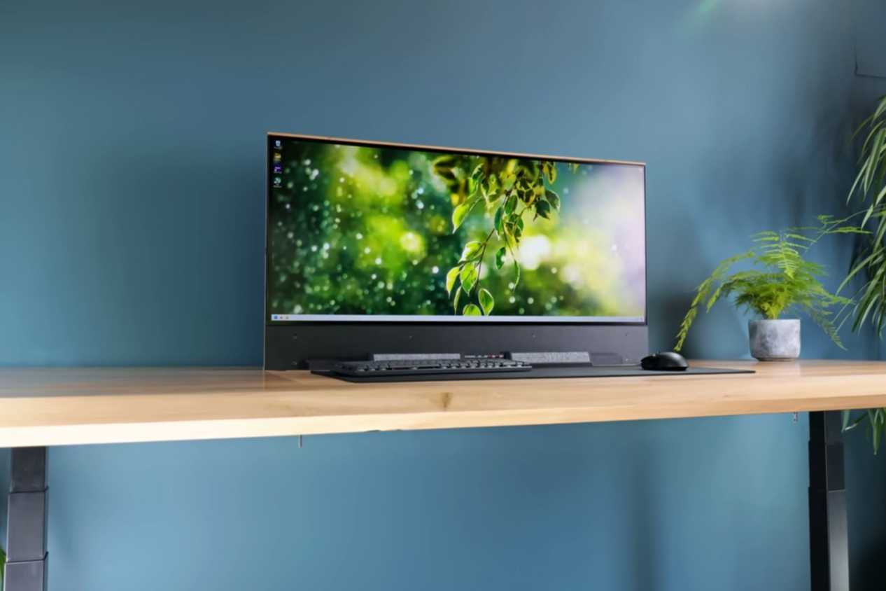 An image showing a monitor resting on a table with peripheral in front of it