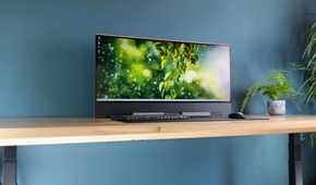 An image showing a monitor resting on a table with peripheral in front of it