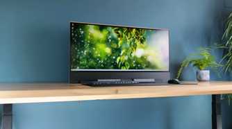 An image showing a monitor resting on a table with peripheral in front of it