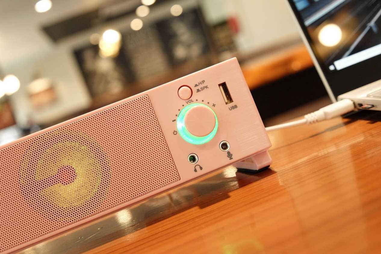 A white PC soundbar on a brown desk