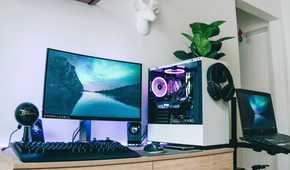 A PC desk setup with a monitor, keyboard, and a PC with a plant on it
