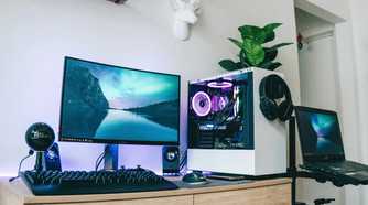 A PC desk setup with a monitor, keyboard, and a PC with a plant on it