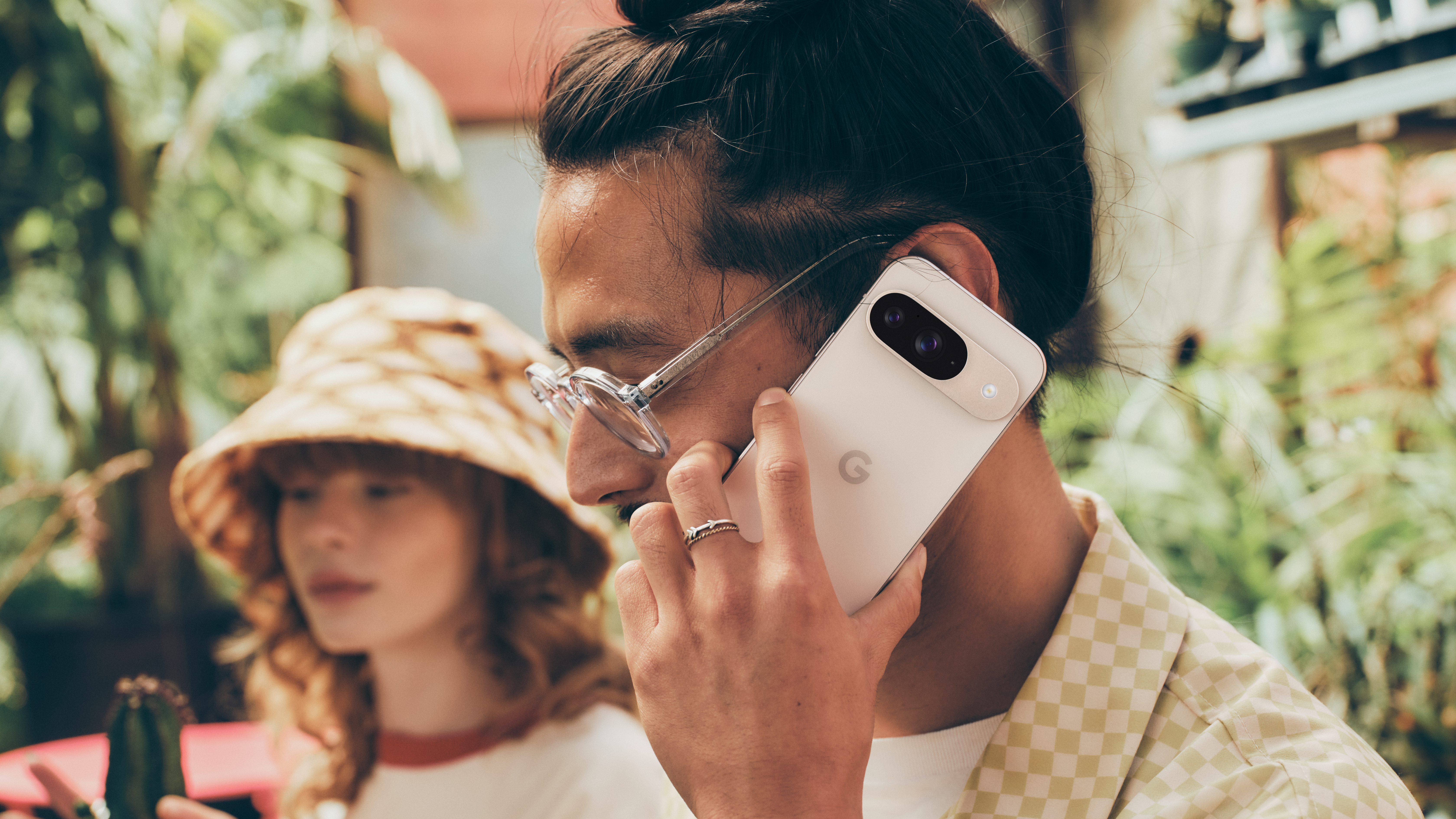 A man holding a Porcelain Google Pixel 9 up to his face for a call