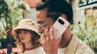 A man holding a Porcelain Google Pixel 9 up to his face for a call