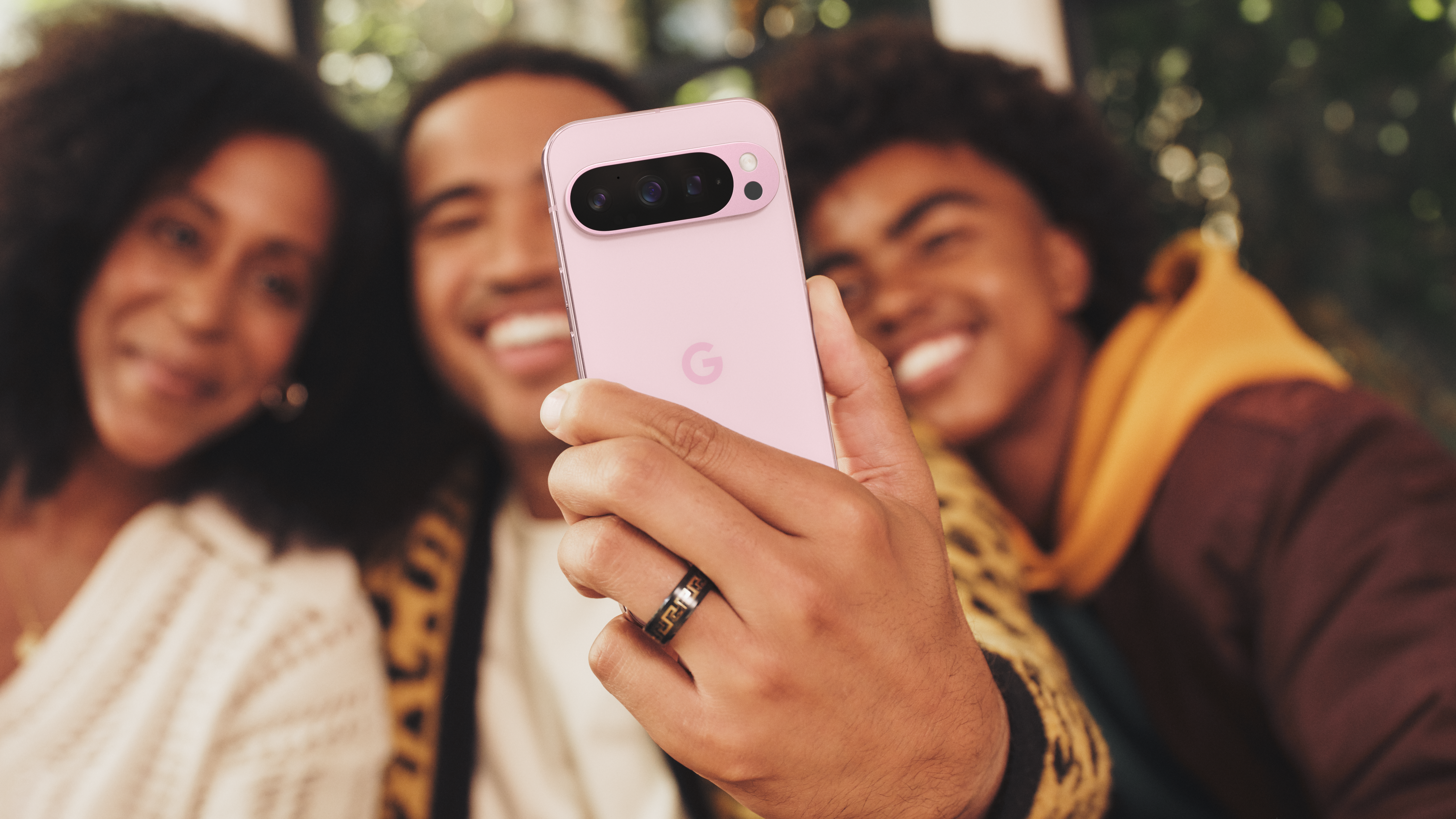 A man taking a group selfie using a Google Pixel 9 Pro in Rose Quartz 